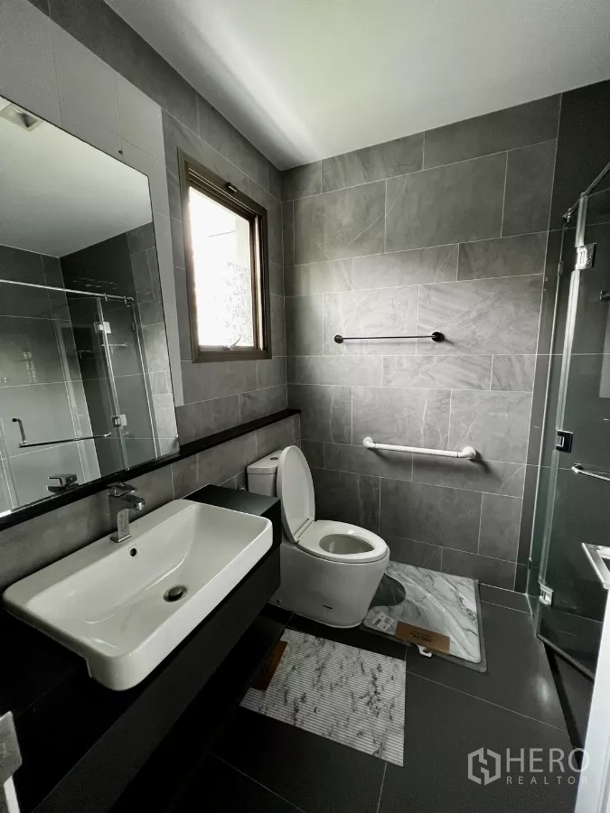 Detached House for rent or sale in Prawet, Bangkok - Contemporary bathroom with vanity, gray tiles and an openable window.