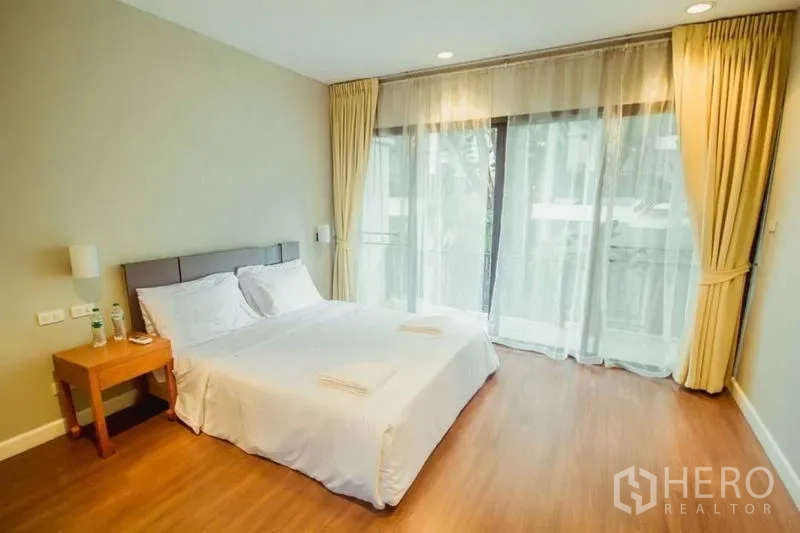 บ้าน ให้เช่าในKhlong Toei, Bangkok - ห้องนอนโปร่งสว่าง เตียงนอน หน้าต่างสูงจรดเพดาน ผ้าม่านโปร่ง และระเบียง.