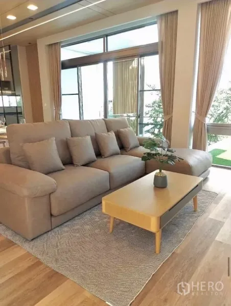 Detached House for rent in Saphan Sung, Bangkok - Cozy lounge with L‑shaped sofa, wooden coffee table and full‑height windows opening to green lawn.