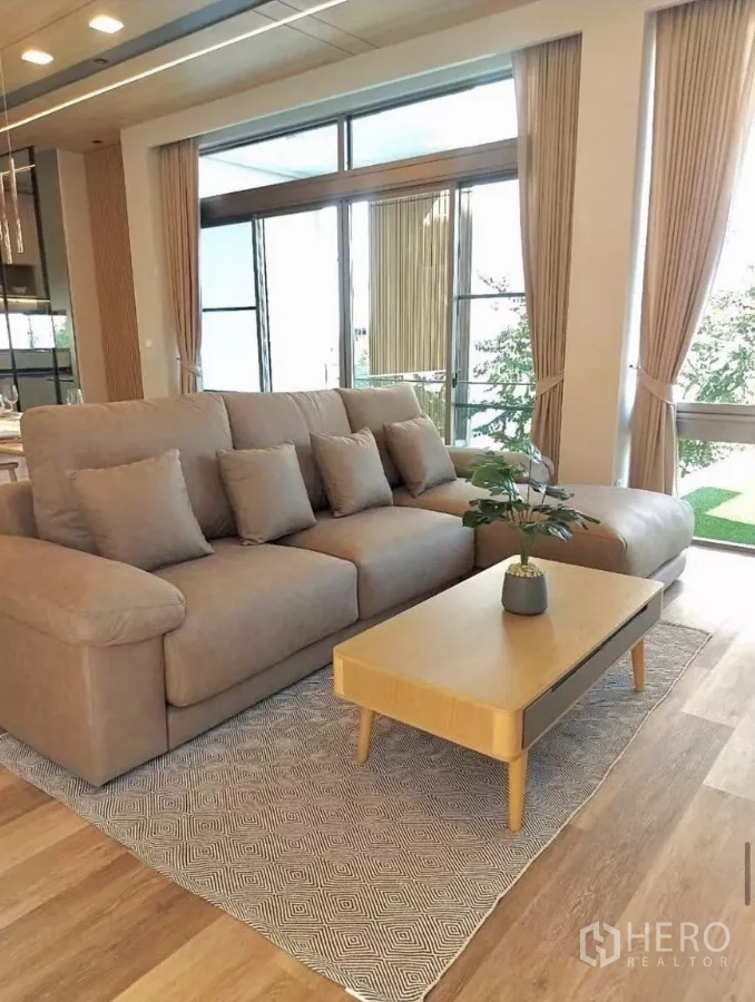 Detached House for rent in Saphan Sung, Bangkok - Cozy lounge with L‑shaped sofa, wooden coffee table and full‑height windows opening to green lawn.