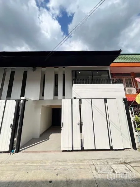 Townhouse for sale in Khlong Toei, Bangkok - Front facade of the renovated townhouse with driveway and sliding gate.