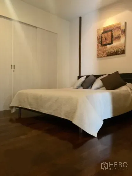 Condominium for rent in Watthana, Bangkok - Minimalist bedroom with double bed, light bedding, built-in wardrobes and wooden floors.