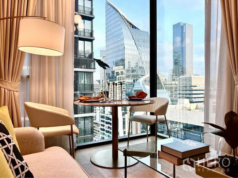 Condominium for rent in Pathum Wan, Bangkok - Round dining table for two beside panoramic window overlooking Bangkok’s skyline.