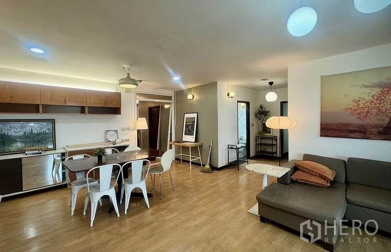 公寓 出租或出售 - 宽敞起居区，转角沙发与餐桌，木地板与暖色照明。