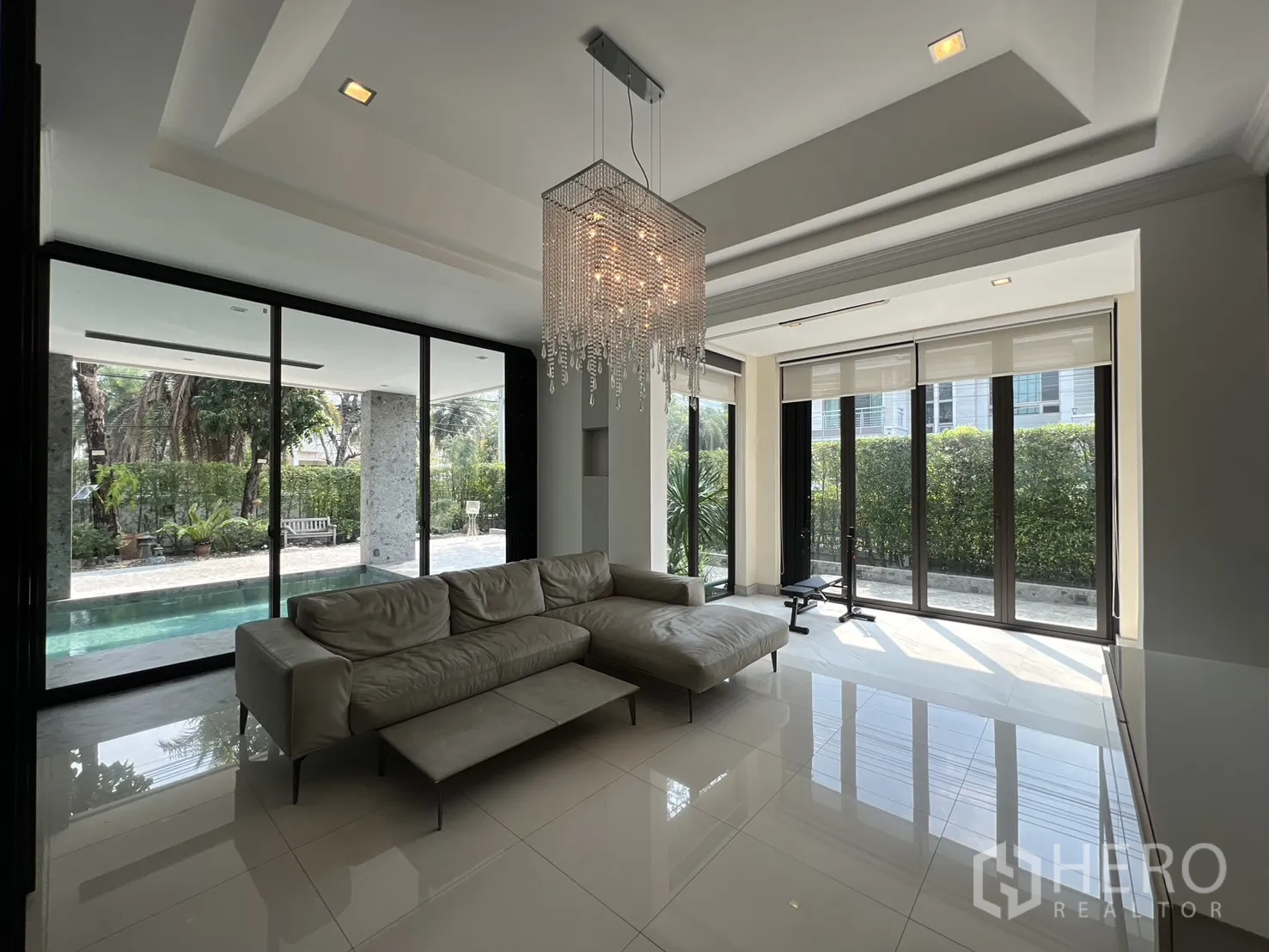 独栋房屋 for rent in Prawet, Bangkok - 明亮客厅，水晶吊灯与转角沙发，窗外花园景观。