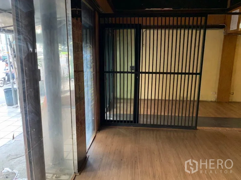 店屋 出租在Watthana, Bangkok - 入口一角，落地玻璃与黑色金属推拉安防门。