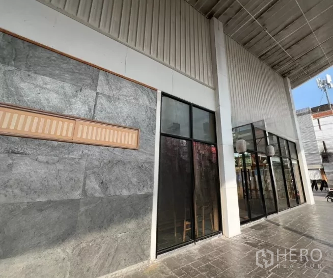 พื้นที่ขายปลีก ให้เช่าในWatthana, Bangkok - ทางเดินมีหลังคา ผนังหินตกแต่ง และช่องแสงสูงตามแนวอาคาร.