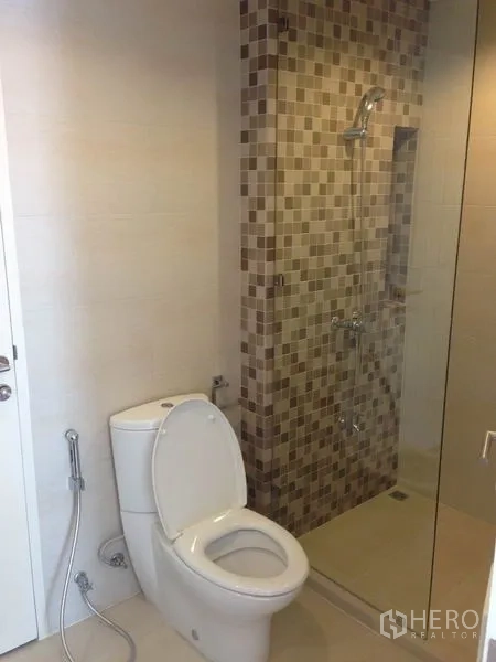 Townhouse for rent in Yan Nawa, Bangkok - Clean bathroom with tiled shower, glass partition, and handheld bidet spray.