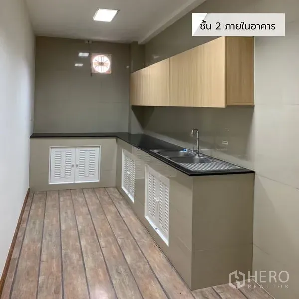 Office Space for rent in Bueng Kum, Bangkok - Office pantry with black countertop, wood cabinets, stainless sink and wood-look flooring.