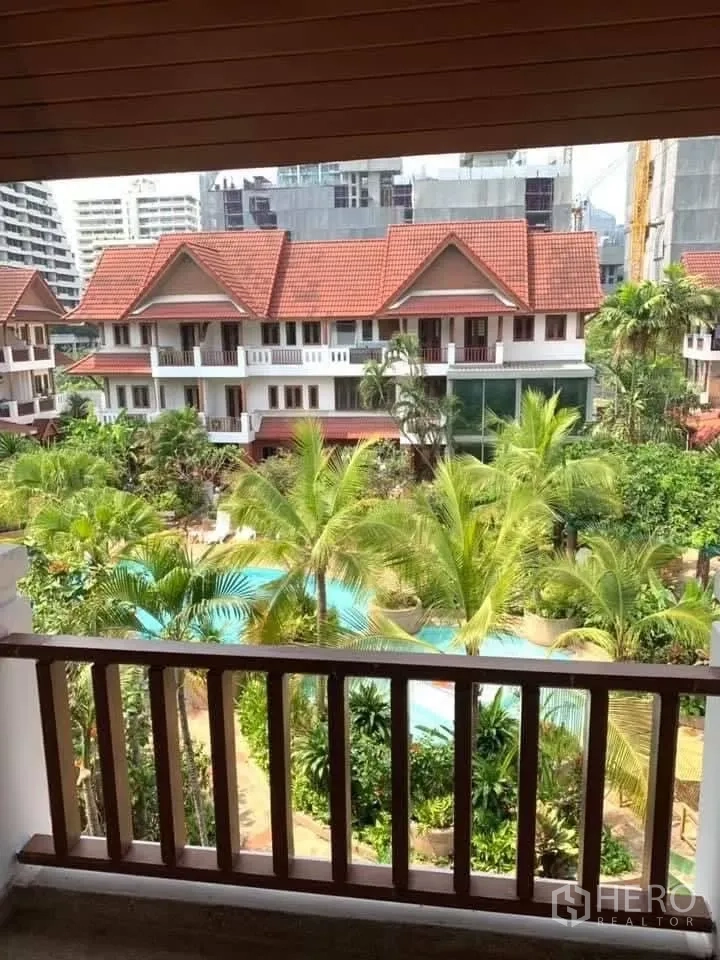 Townhouse for rent in Watthana, Bangkok - Balcony view over tropical garden and pool with townhouse roofs.