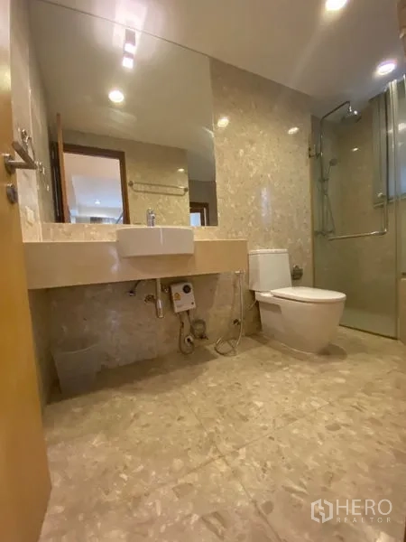 公寓 出租在Watthana, Bangkok - 第二卫浴设台盆、马桶与玻璃淋浴房，石纹铺面。