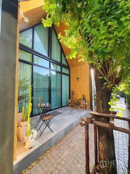 Detached House for sale in Bang Khun Thian, Bangkok - Shaded front patio with A-frame glass facade, floor-to-ceiling windows and garden seating.