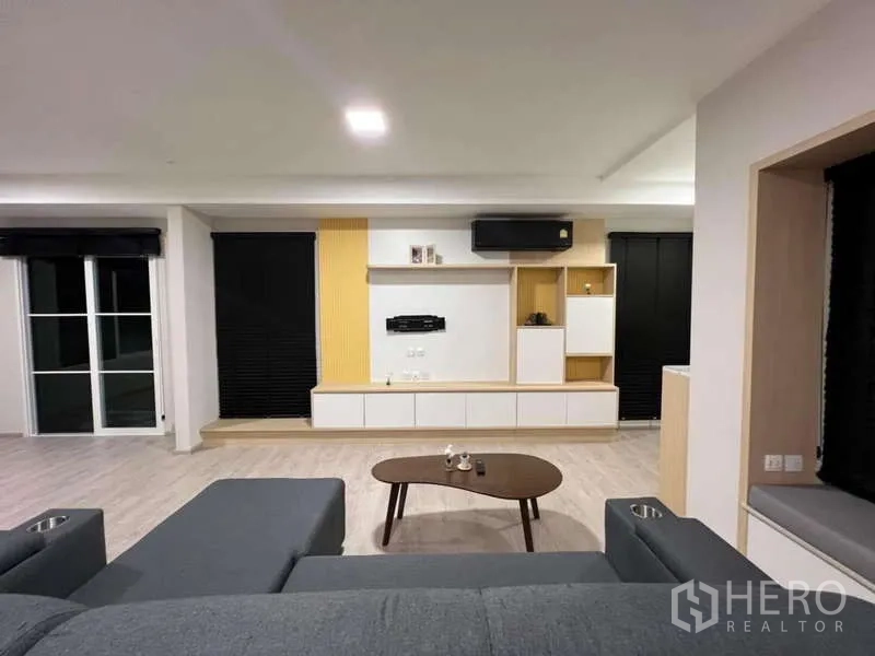 Detached House for rent in Prawet, Bangkok - TV wall with floating cabinets and media console between large windows.