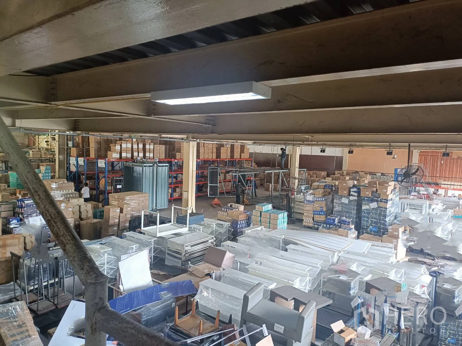 Warehouse for rent in Lam Luk Ka, Pathum Thani - Mezzanine view over the warehouse floor with racking and packaged inventory.