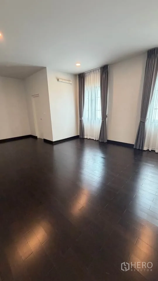 Detached House for rent in Bang Phli, Samut Prakan - Bright room with multiple corner windows and dark wood floors.