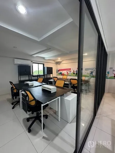 Home Office for rent - Open-plan office with desks and orange chairs behind a glass partition.