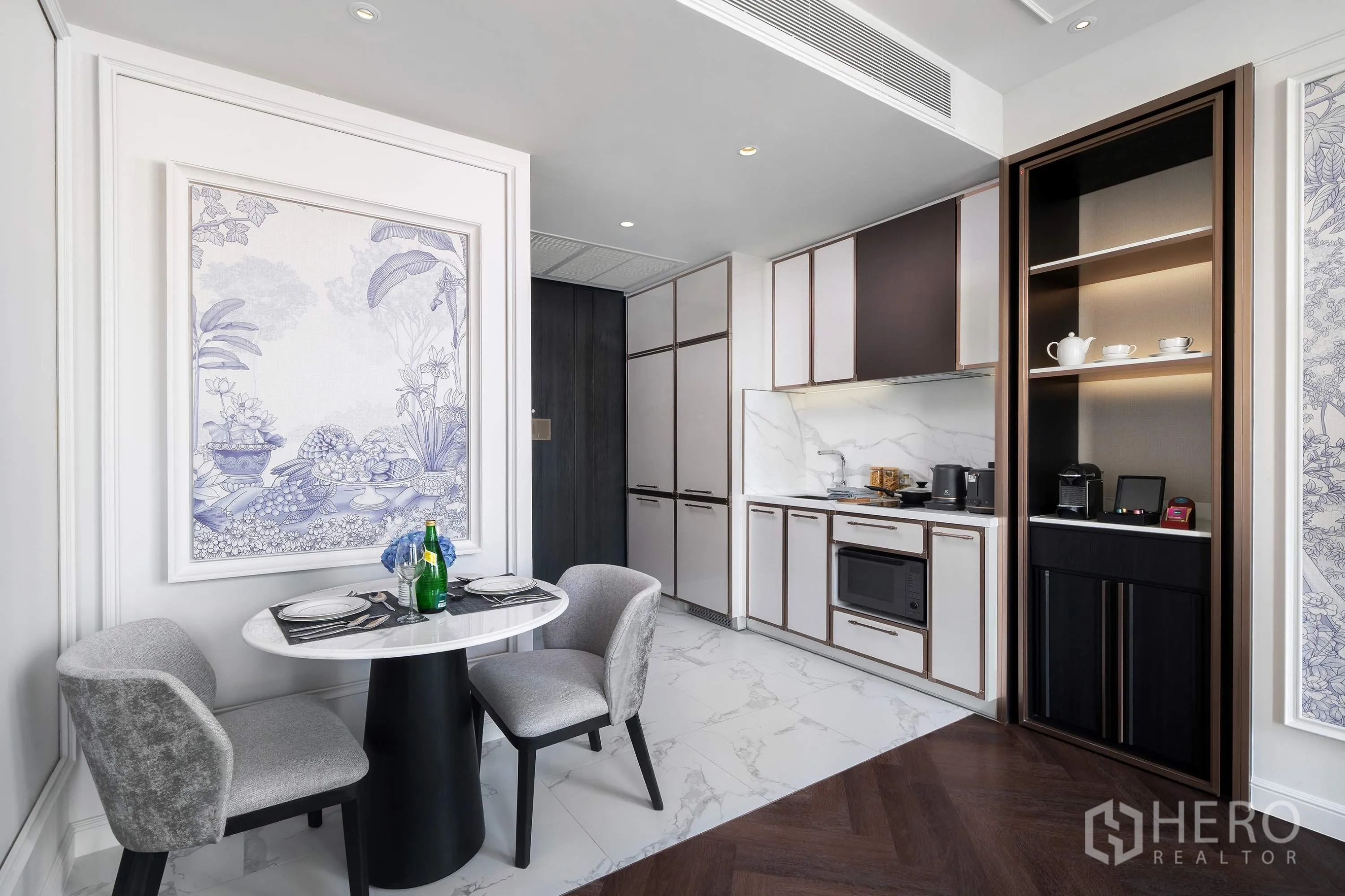Condominium for rent in Khlong Toei, Bangkok - Compact kitchen with marble backsplash, built-in cabinets, microwave, and a two-seat dining set.