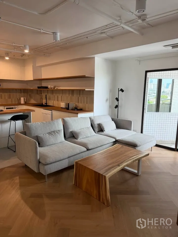 Condominium for rent in Watthana, Bangkok - Living area facing open kitchen and balcony with city outlook.