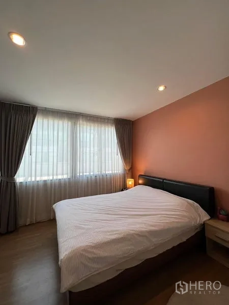 ทาวน์เฮาส์ ให้เช่าในSaphan Sung, Bangkok - ห้องนอนสว่างพร้อมหน้าต่างบานใหญ่ ผนังโทนพีช และเตียงควีนพร้อมโคมหัวเตียง