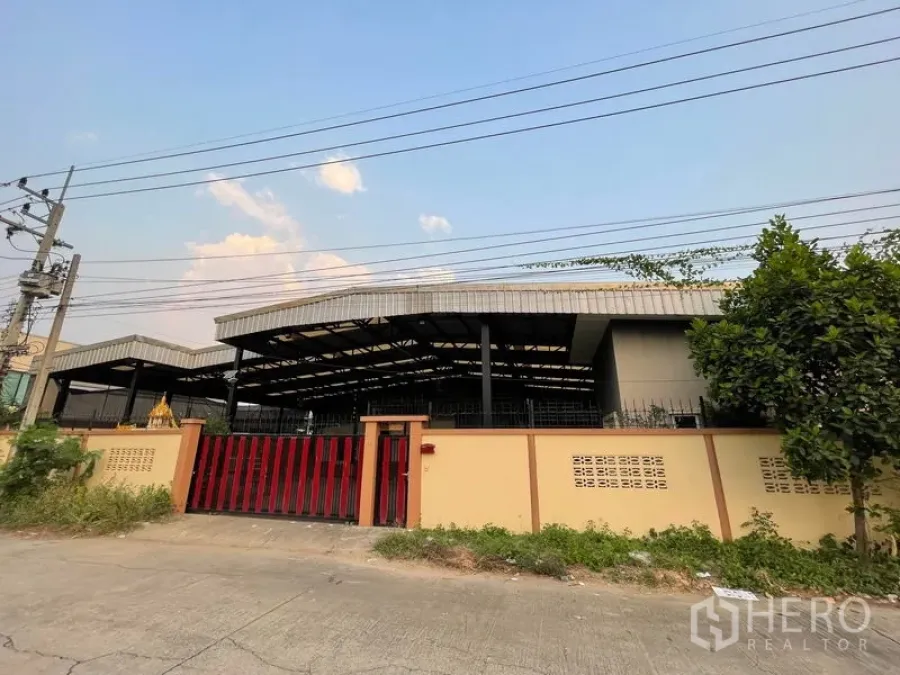工厂 出租在Lat Lum Kaeo, Pathum Thani - 临街外立面，黄色围墙与红色推拉大门。