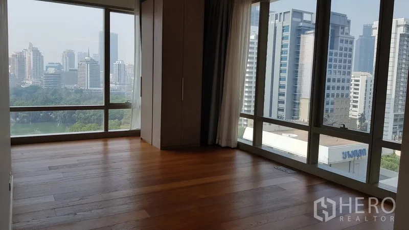 Condominium for rent in Pathum Wan, Bangkok - Corner bedroom with large windows and panoramic skyline and park views.