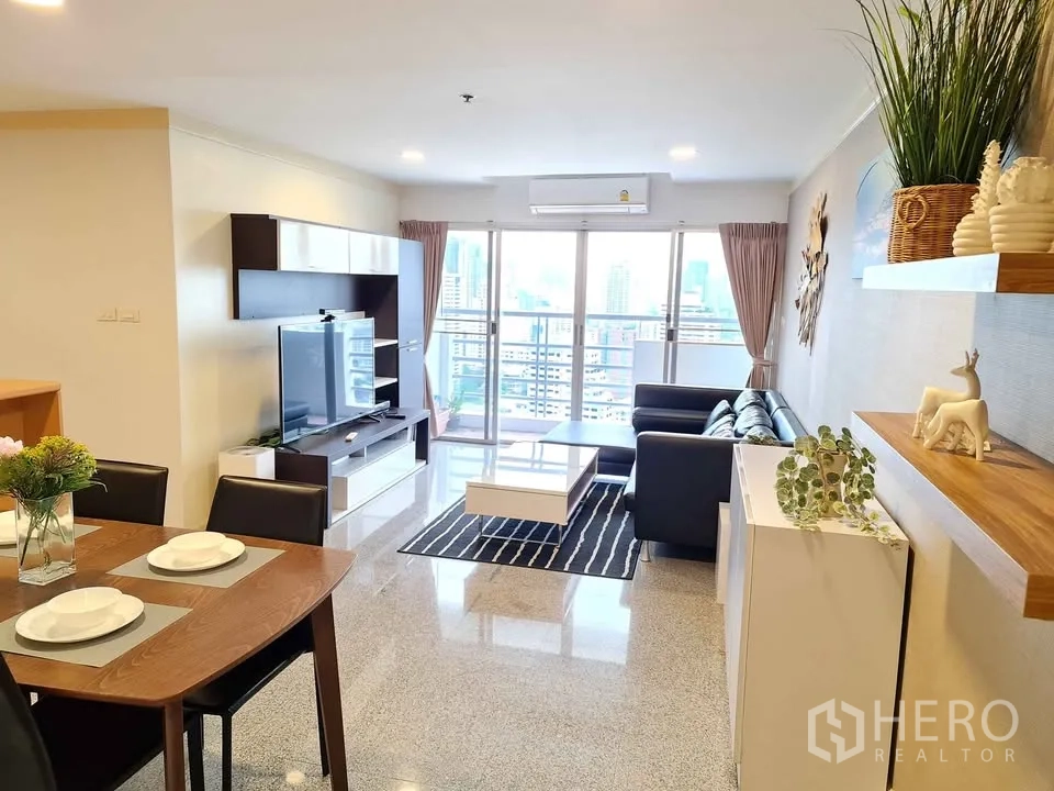 Condominium for rent in Khlong Toei, Bangkok - Living room with TV unit facing sofa and access to balcony.