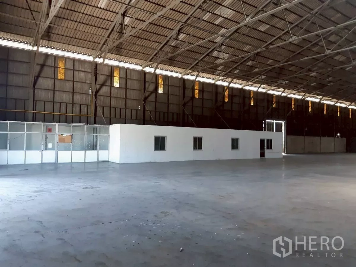 Warehouse for rent in Pak Kret, Nonthaburi - Large warehouse interior with high steel truss roof, polished concrete floor and an internal office block.