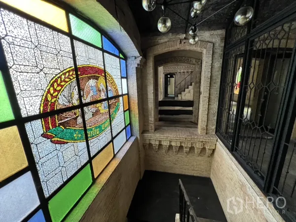 零售空间 出租在Watthana, Bangkok - 室内走廊，设有大型彩色玻璃窗、裸露砖拱和楼梯。