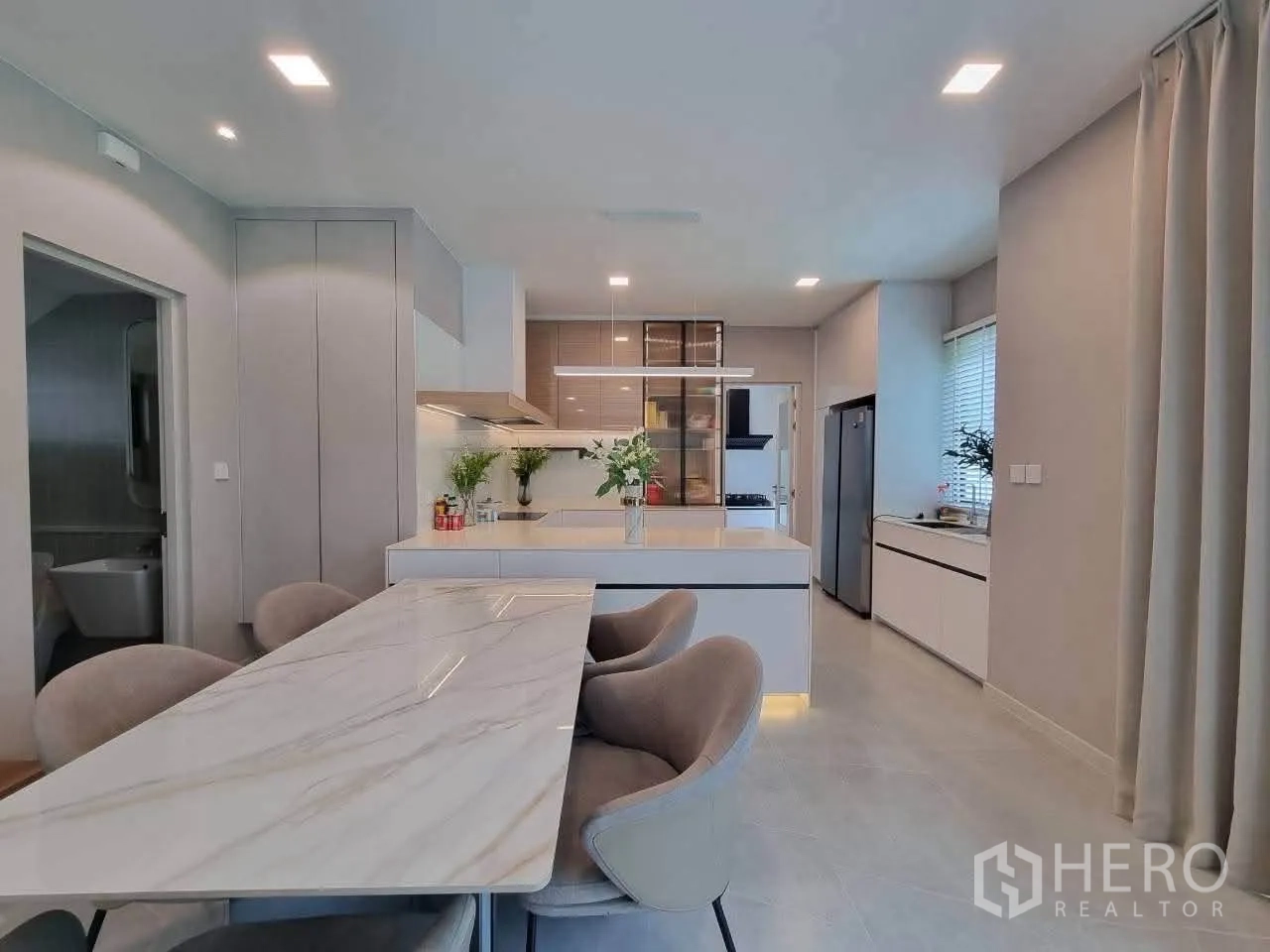 Detached House for rent in Bang Phli, Samut Prakan - Dining area beside contemporary kitchen with island, cabinets and appliances.