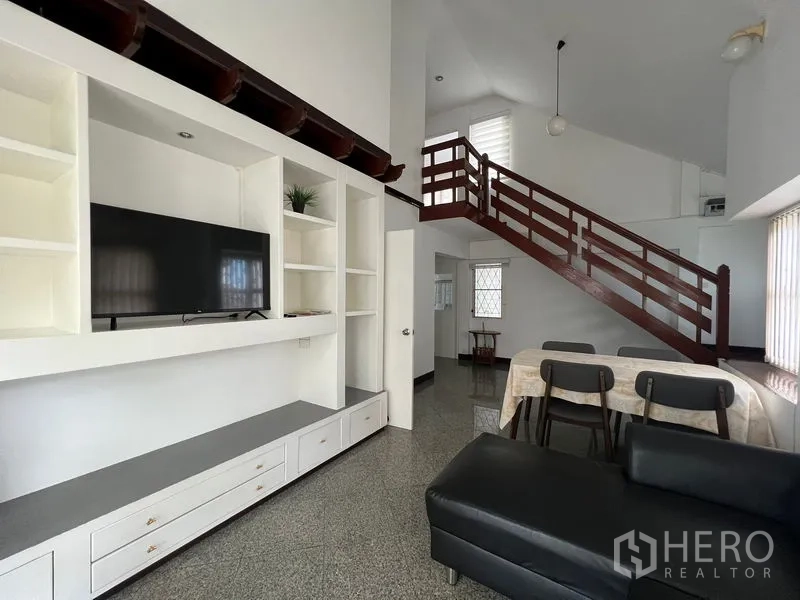 Detached House for rent in Saphan Sung, Bangkok - Open-plan lounge and dining area with TV wall unit and wooden staircase.