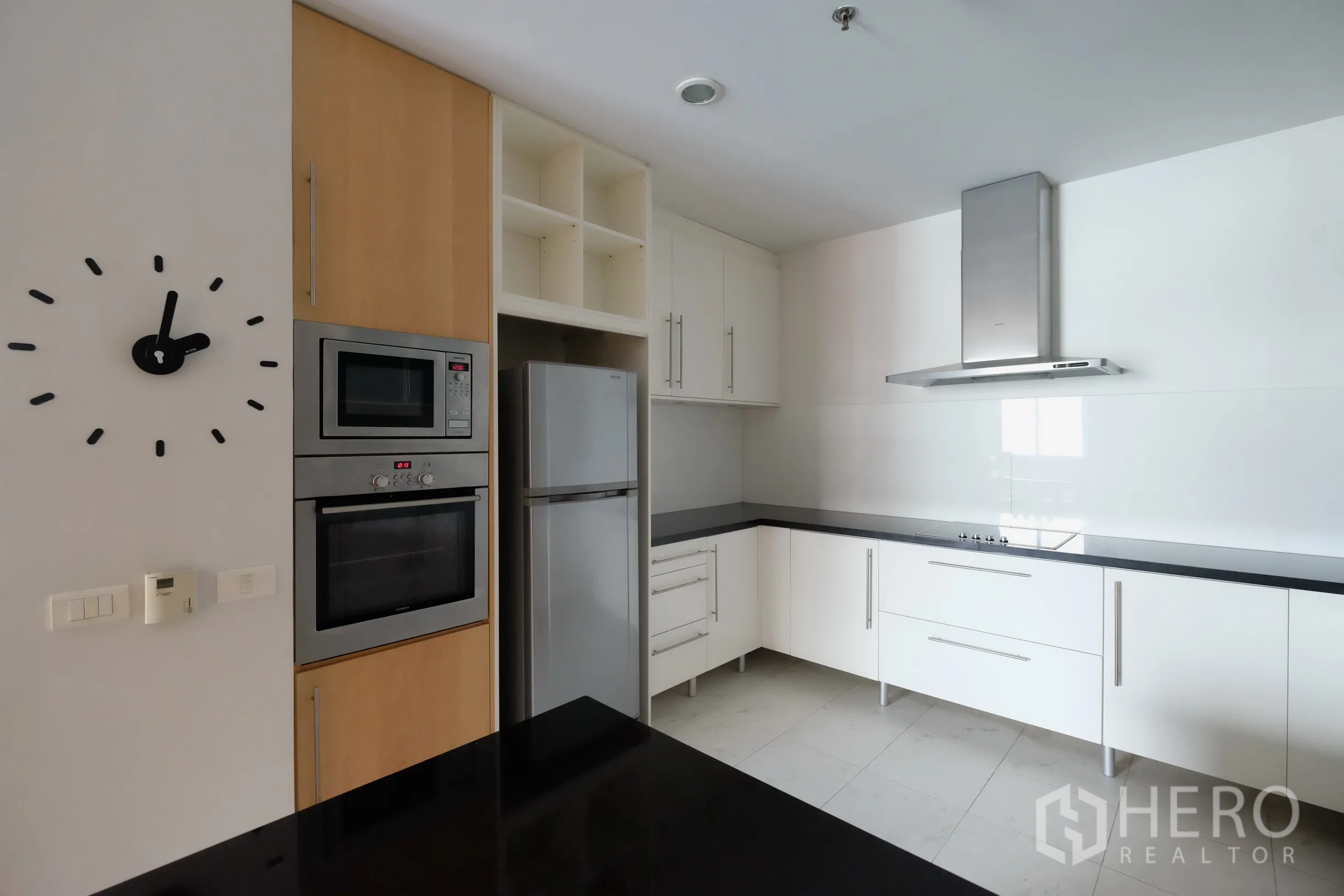 公寓 出租在Bang Rak, Bangkok - 全配套厨房，白色橱柜、黑色台面、烤箱、微波炉与不锈钢冰箱。