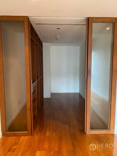Condominium for rent in Yan Nawa, Bangkok - Walk-in closet area with wooden flooring, built-in shelving and sliding glass doors.