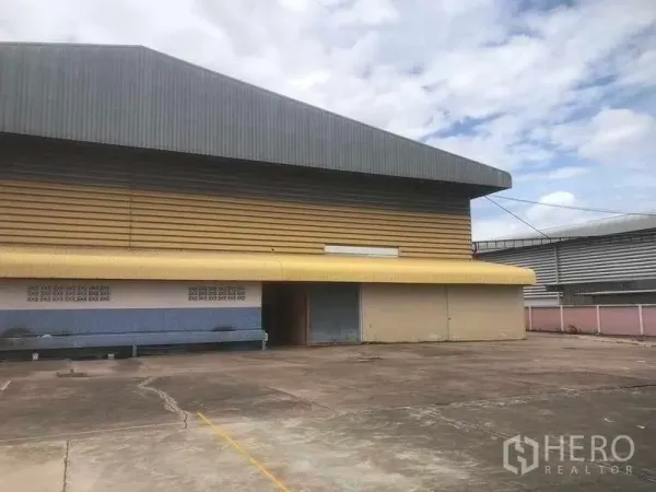 Warehouse for sale in Rayong - Side elevation of the warehouse with loading dock, canopy and roller shutters.