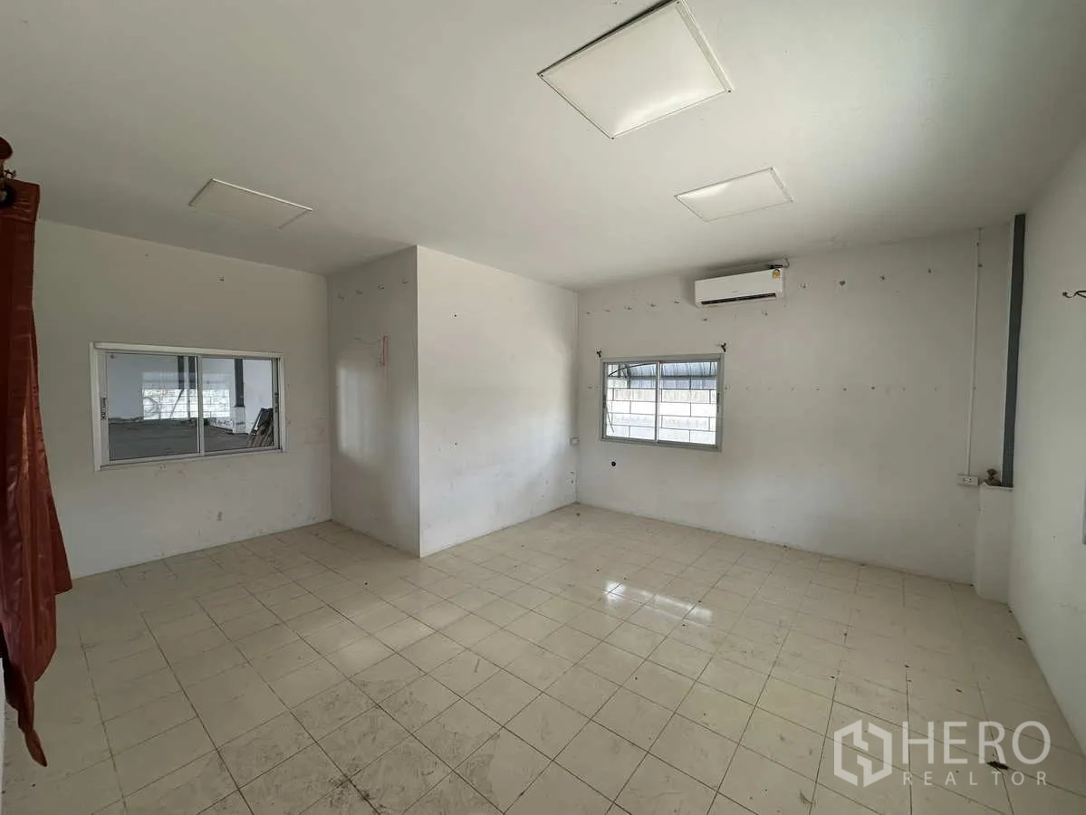 Factory for rent in Pathum Thani - Air-conditioned office room with tiled flooring and windows overlooking the factory.