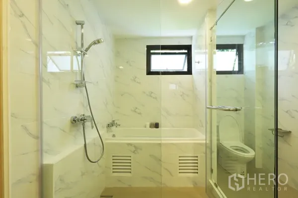 Condominium for rent in Watthana, Bangkok - Bathroom featuring a soaking tub, separate glass shower and small windows for natural light.