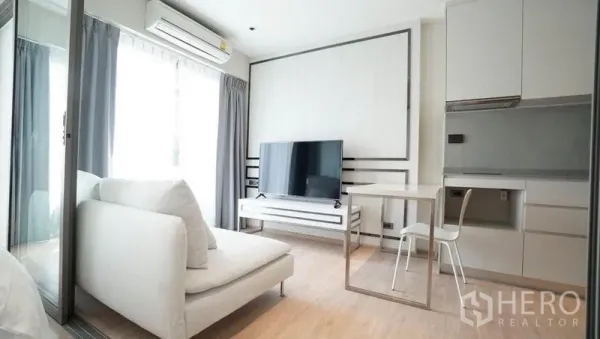 公寓 出售在Khlong Toei, Bangkok - 采光充足的客厅，白色沙发、大屏电视、双人餐桌与紧凑小厨房。