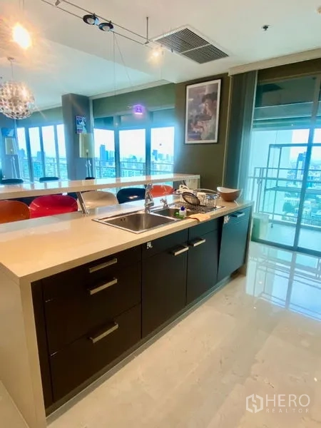 公寓 出租在Watthana, Bangkok - 开放式厨房，长岛台、洗涤槽与早餐吧，采光充足。