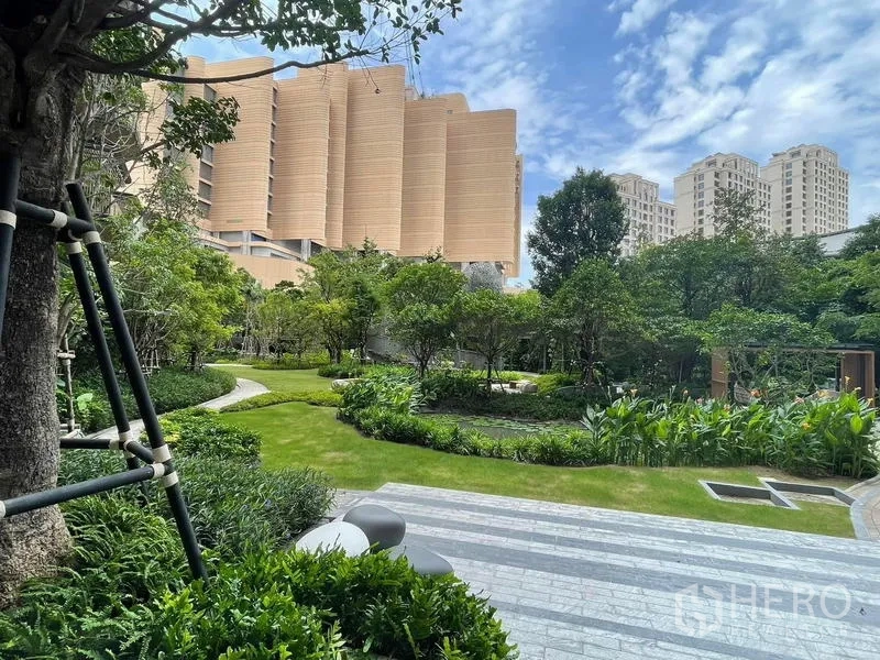 Condominium for rent in Samut Prakan - Lush landscaped garden with curved pathways and mature trees.