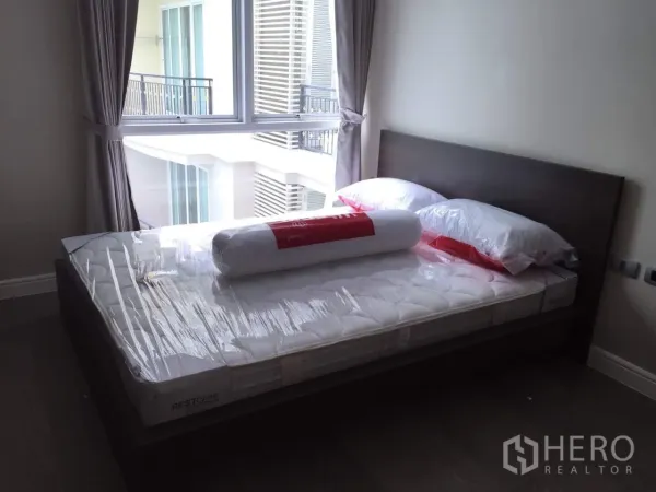 คอนโด ให้เช่าในKhlong Toei, Bangkok - ห้องนอนมีหน้าต่างบานใหญ่ ผ้าม่านสีเทา และเตียงพร้อมที่นอนใหม่