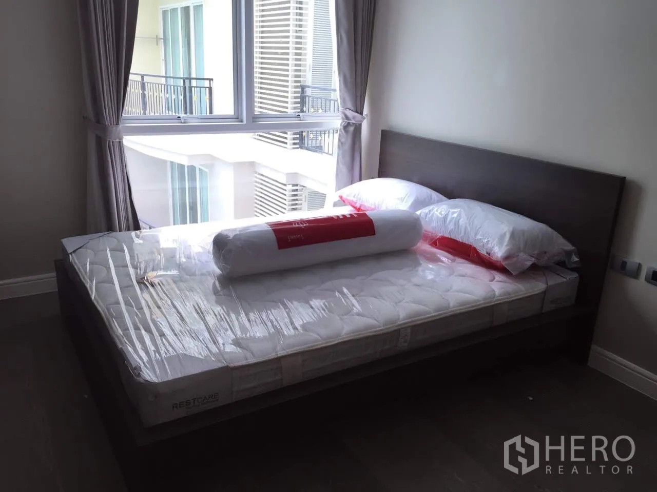 คอนโด ให้เช่าในKhlong Toei, Bangkok - ห้องนอนมีหน้าต่างบานใหญ่ ผ้าม่านสีเทา และเตียงพร้อมที่นอนใหม่