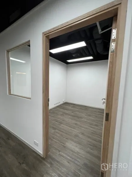 办公空间 出租在Khlong Toei, Bangkok - 通往另一间办公室的门洞，设内窗和外露管线