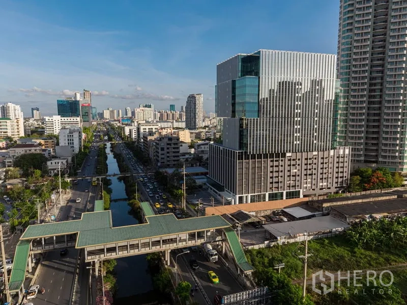 Office Space for rent in Bang Rak, Bangkok - Aerial view of a contemporary office building by a main road, canal and skywalk near BTS in Bangkok.