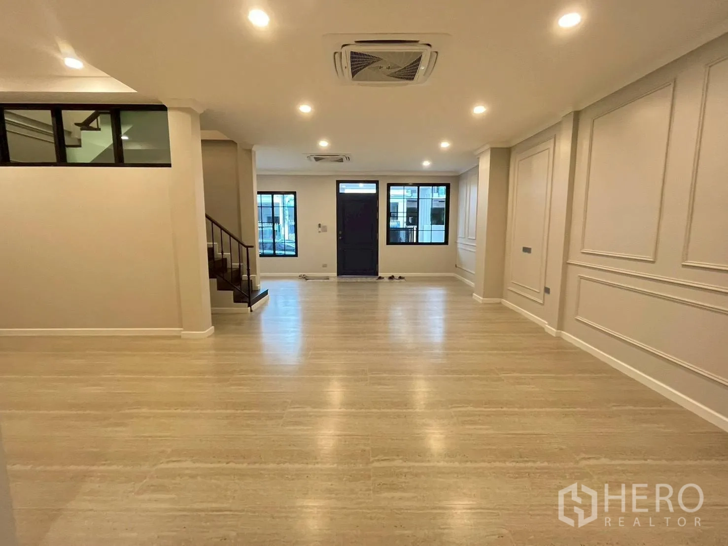 ทาวน์เฮาส์ for rent in Khlong Toei, Bangkok - มุมกว้างของห้องนั่งเล่นใหญ่ ไฟดาวน์ไลต์ ผนังบัวปูน และประตูทางเข้า.