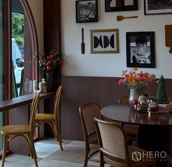 零售空间 出租在Watthana, Bangkok - 窗边吧台座位，木质高脚椅与花艺摆设、装饰画。