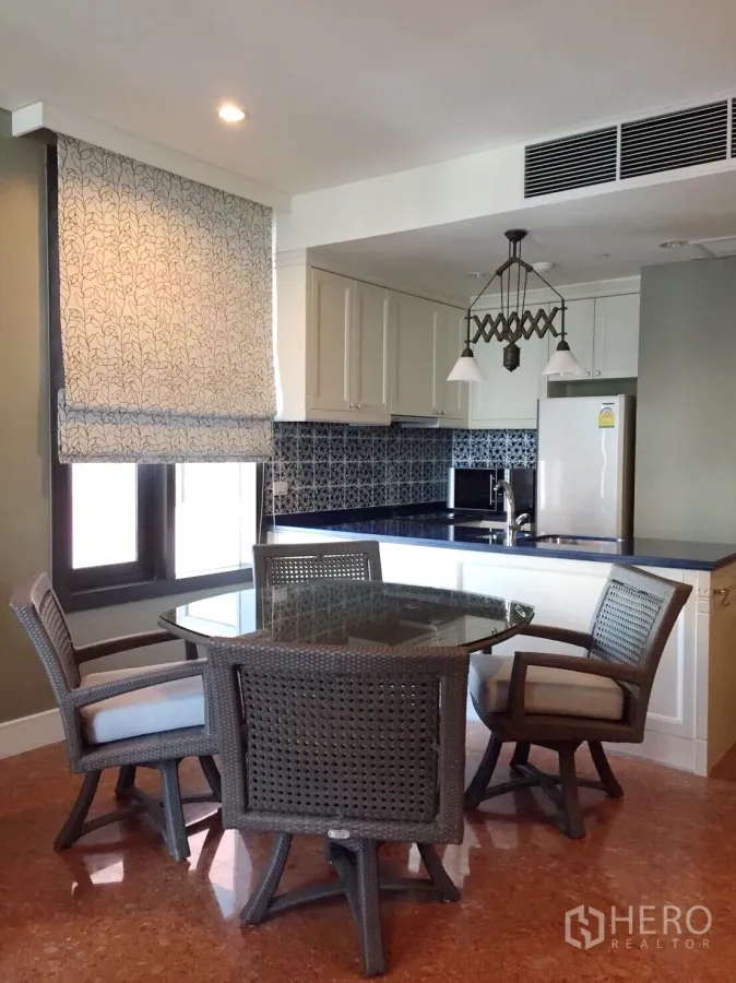 คอนโด ให้เช่าในKhlong Toei, Bangkok - พื้นที่รับประทานอาหารของคอนโดในคลองเตย โต๊ะกระจกพร้อมเก้าอี้หวาย และครัวเปิดเคาน์เตอร์สีน้ำเงิน