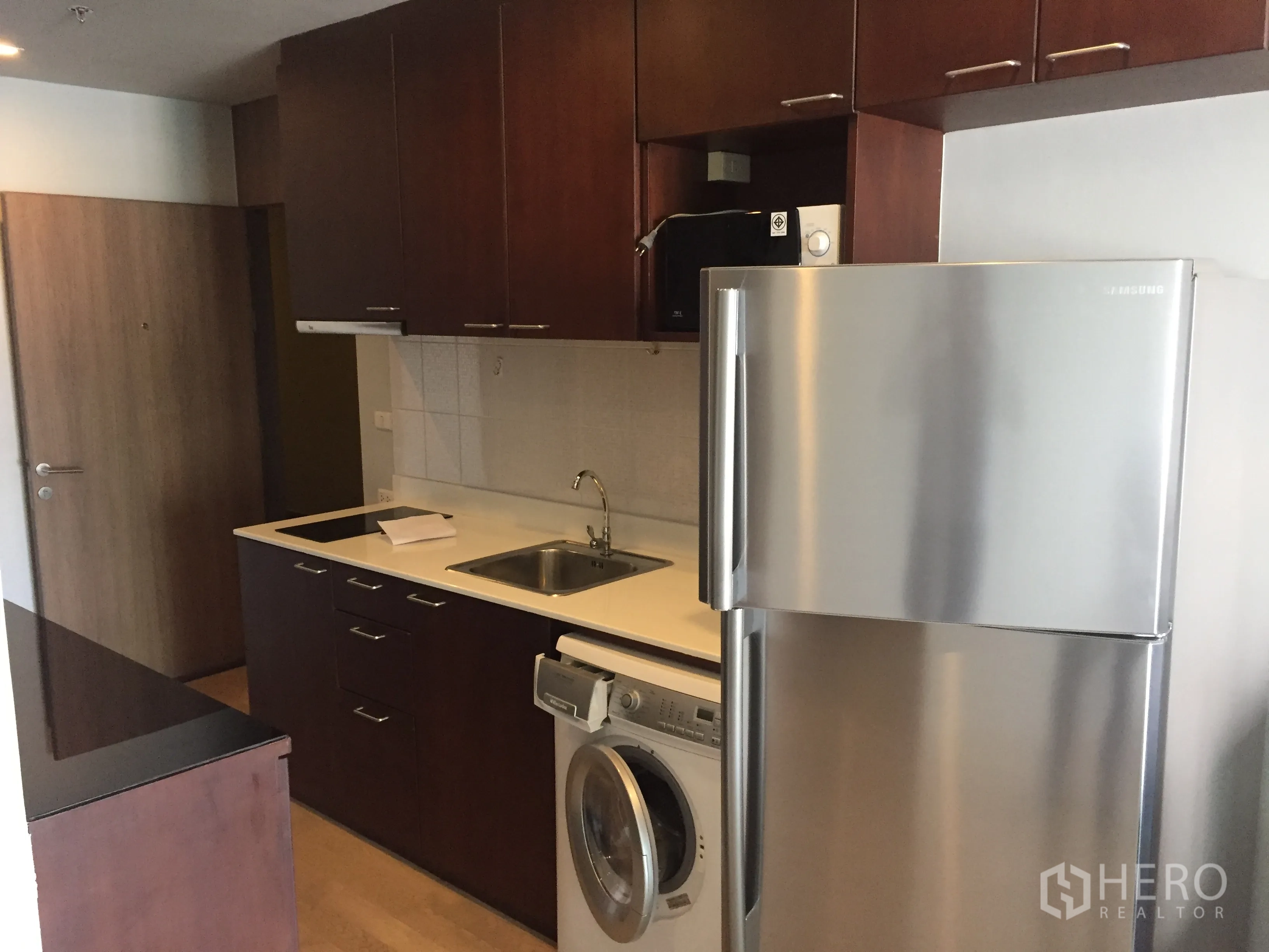 คอนโด ให้เช่าในBangkok - ครัวบิวท์อินตู้ไม้สีเข้ม ท็อปสีขาว พร้อมตู้เย็นสแตนเลสและเครื่องซักผ้า