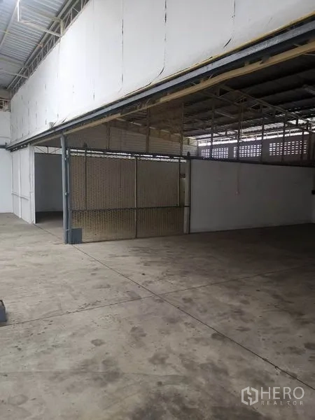 Warehouse for rent in Suan Luang, Bangkok - Wide loading area beside a gated storage section inside the warehouse.