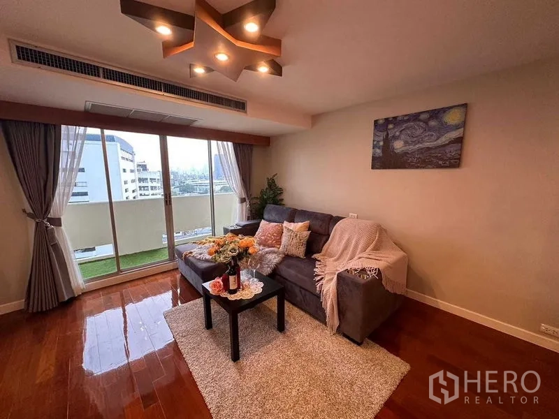 คอนโด ให้เช่าในKhlong Toei, Bangkok - มุมห้องนั่งเล่นอีกด้านพร้อมโซฟา พรม โต๊ะกาแฟ และหน้าต่างสูงจรดเพดานออกสู่ระเบียง