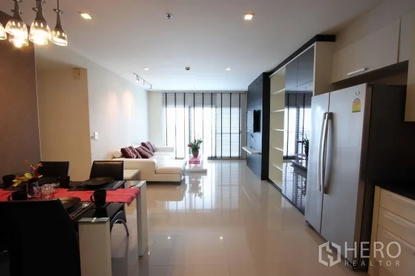 公寓 出租在Khlong Toei, Bangkok - 开放式客餐区，白色转角沙发、落地窗、亮面地砖与电视墙