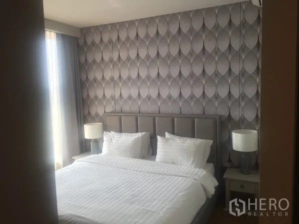 คอนโด ให้เช่าในKhlong Toei, Bangkok - ห้องนอนอบอุ่นด้วยวอลเปเปอร์ลายกราฟิก เตียงขนาดใหญ่และโคมไฟหัวเตียง